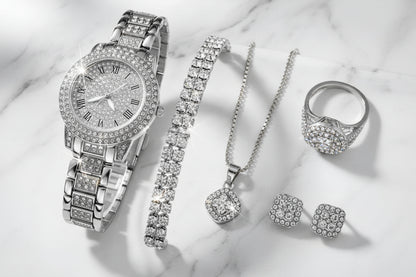 Silver jewelry set including a watch, bracelet, necklace, ring, and earrings on a black background.